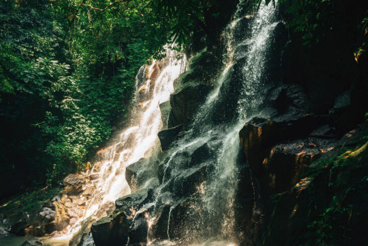 kanto lampo waterfall gianyar bali scenic seasonal waterfall cascading down stepped rock wall into shallow wading pool